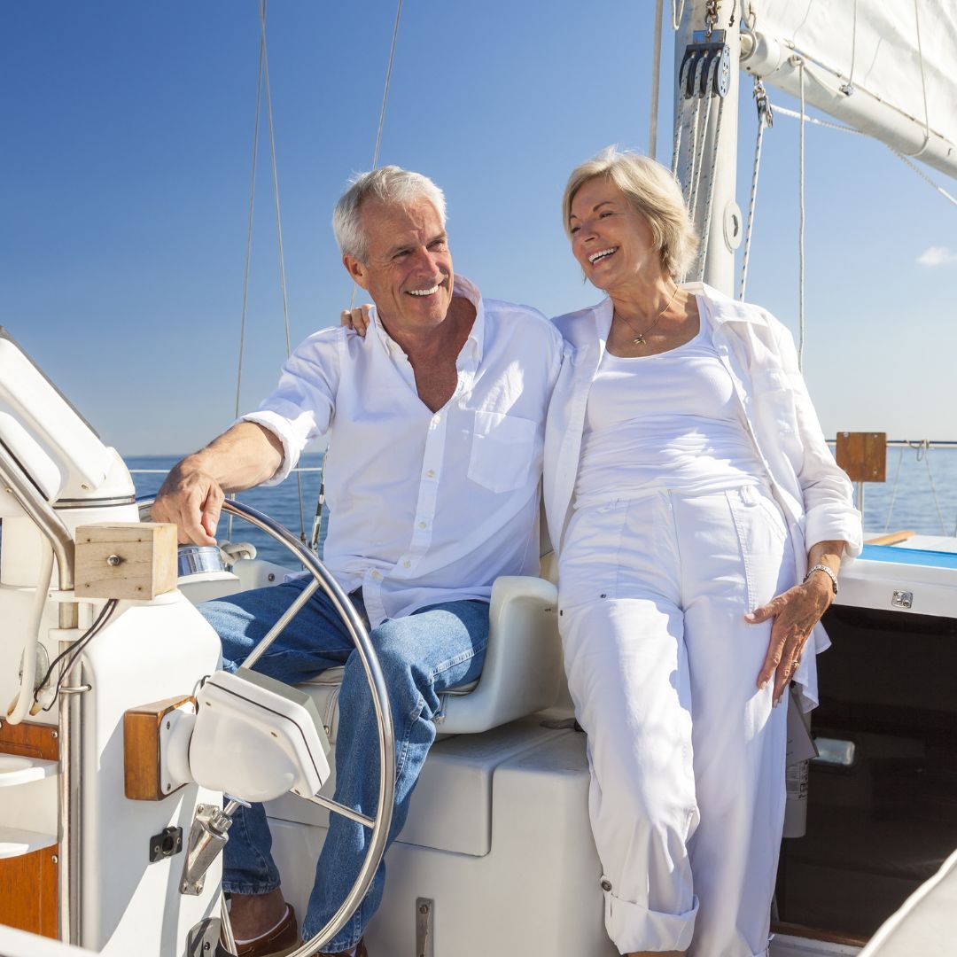 A senior couple enjoying a peaceful moment together on a sailboat, surrounded by calm waters and clear skies.