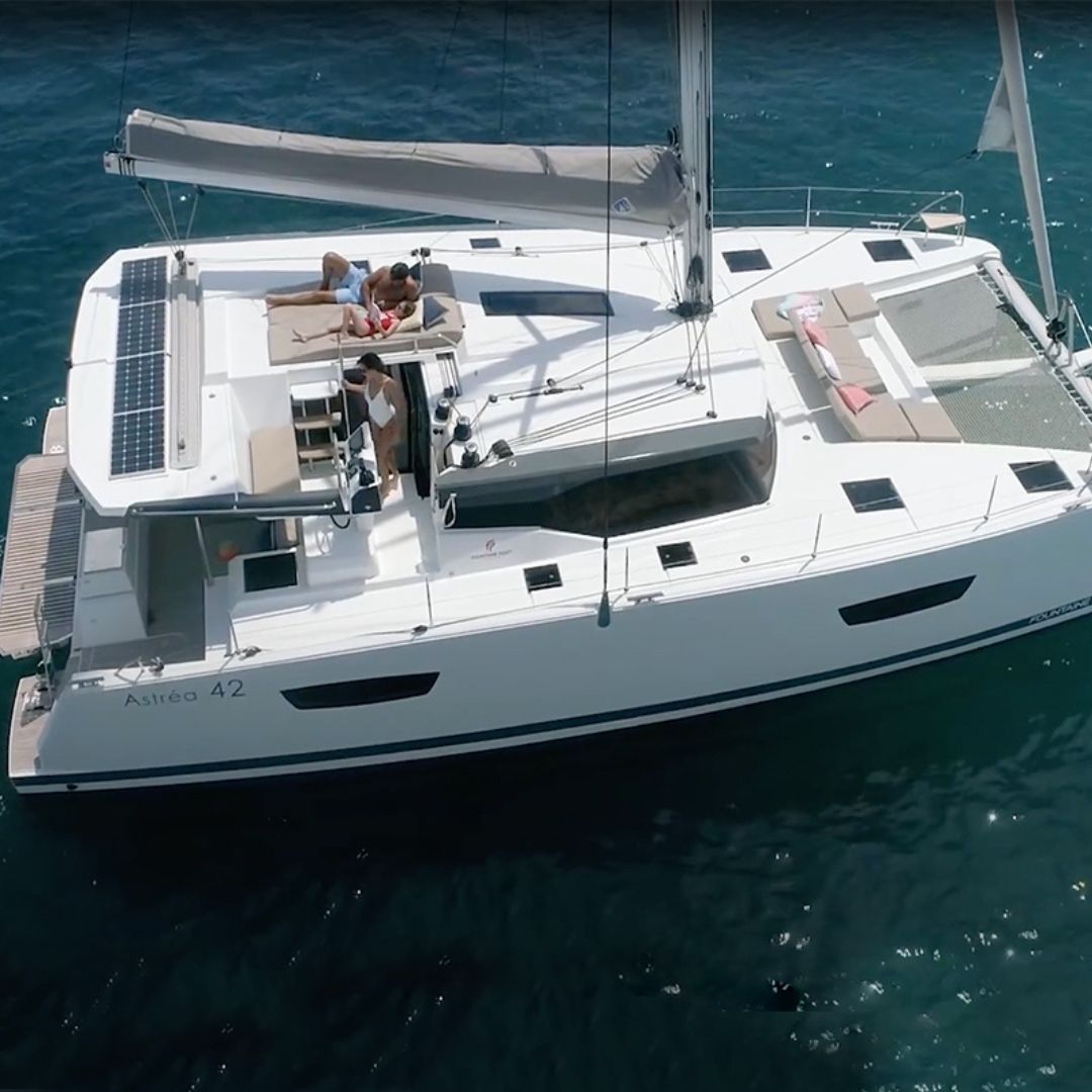 A catamaran floats on the water, occupied by several people enjoying their time on board.