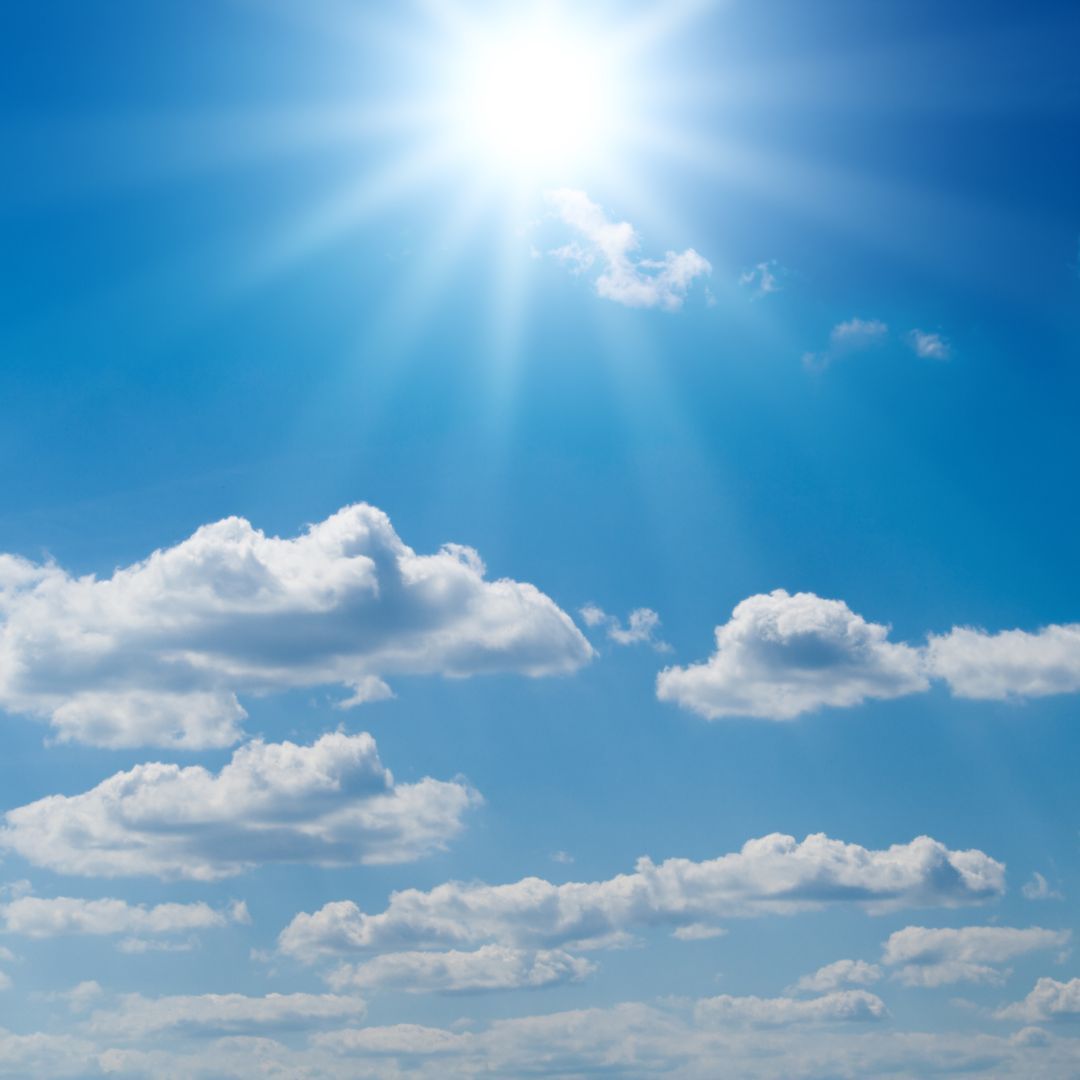 A bright sun illuminates a clear blue sky, creating a vibrant and cheerful atmosphere.