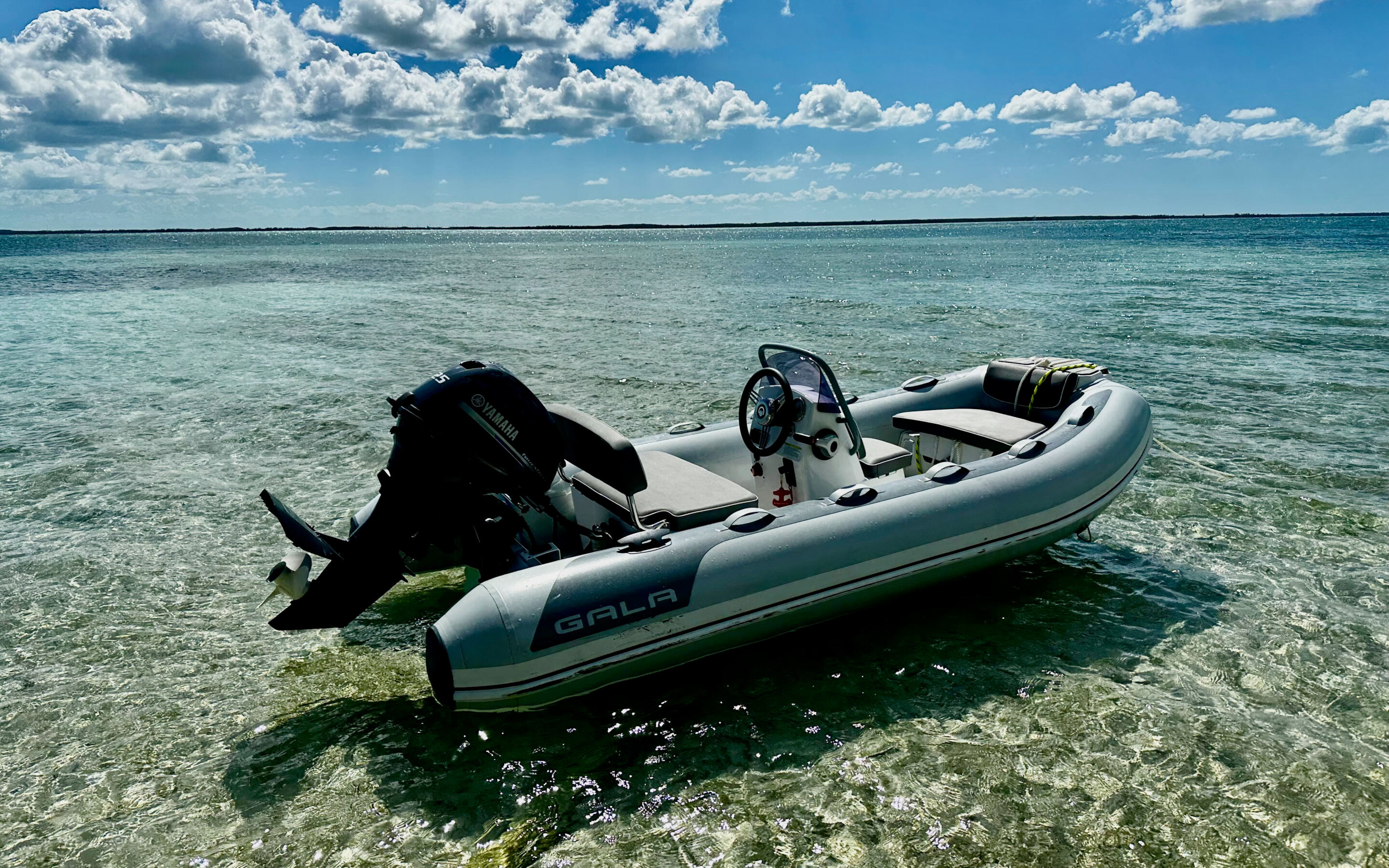 A motor boat floats in shallow water under a clear blue sky, creating a serene and picturesque scene.
