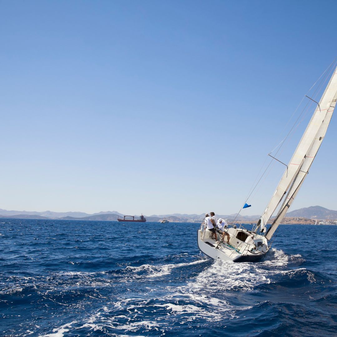 A sailboat gliding gracefully across the vast, open ocean under a clear blue sky.