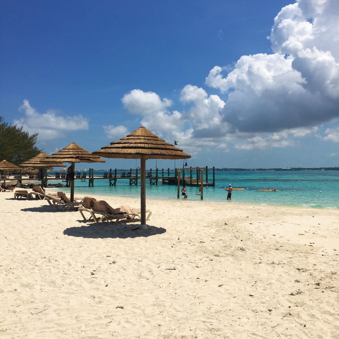 Beach chairs and colorful umbrellas arranged on a sandy beach, inviting relaxation under the sun.