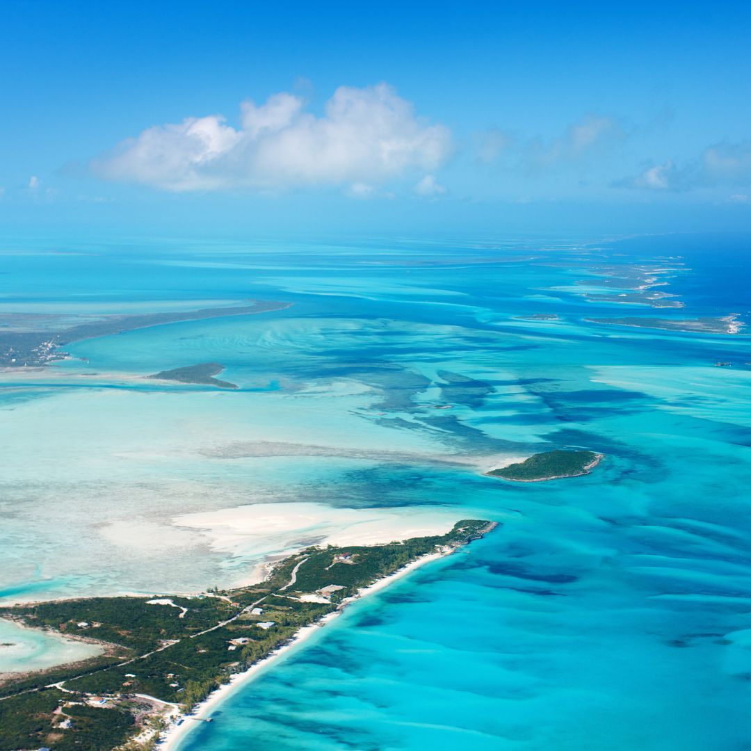 Aerial view showcasing the vibrant turquoise waters of a serene lagoon, surrounded by lush greenery and sandy shores.