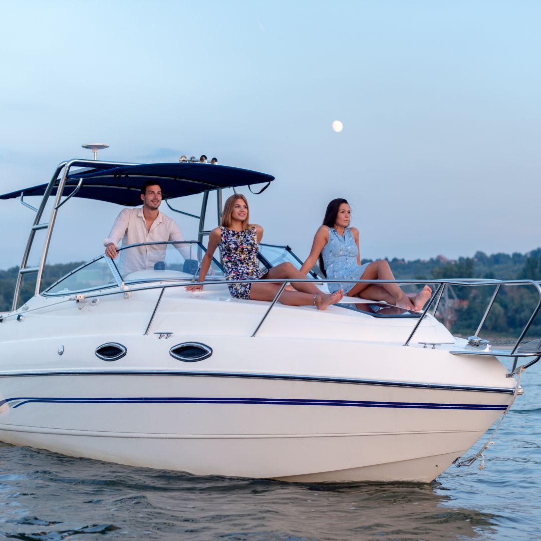 A family of three enjoys a ride on a white motorboat, with the sun shining and water splashing around them.