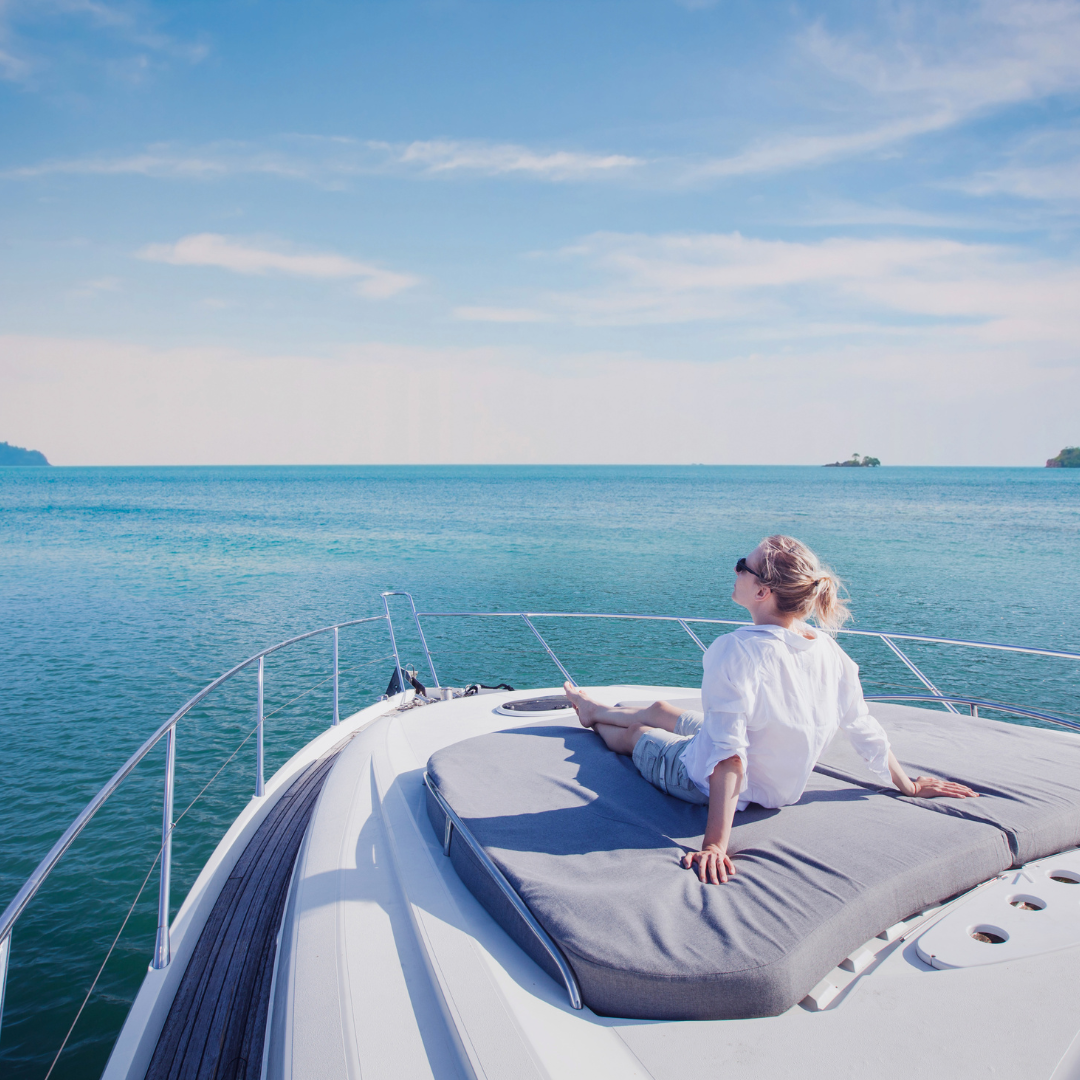A woman sits on the back of a boat, enjoying the view and the gentle sway of the water around her.