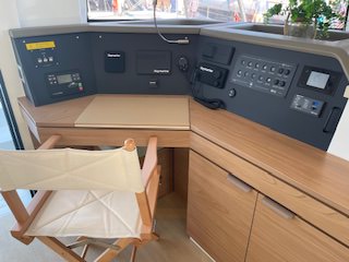 A desk in a boat featuring a chair and a computer, showcasing a unique workspace on the water.