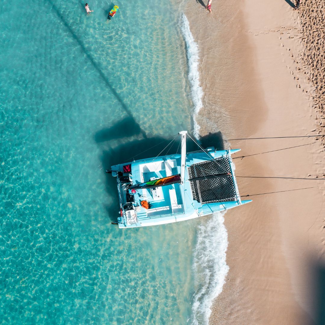 A boat rests on the beach, surrounded by people enjoying the sun and sand.