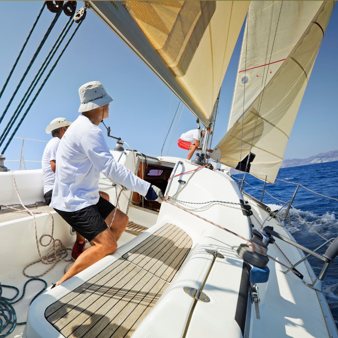 Three men enjoying sailing together on a sailboat, surrounded by calm waters and a clear sky.
