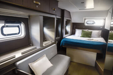 A cozy small boat interior featuring a comfortable bed and a plush couch, ideal for relaxation on the water.