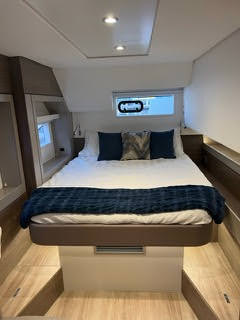 A cozy boat interior featuring a comfortable bed and a functional desk, showcasing a serene maritime atmosphere.