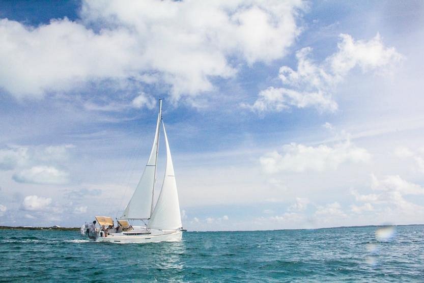 A sailboat glides across the ocean, surrounded by a clear blue sky, creating a serene maritime scene.<br />

