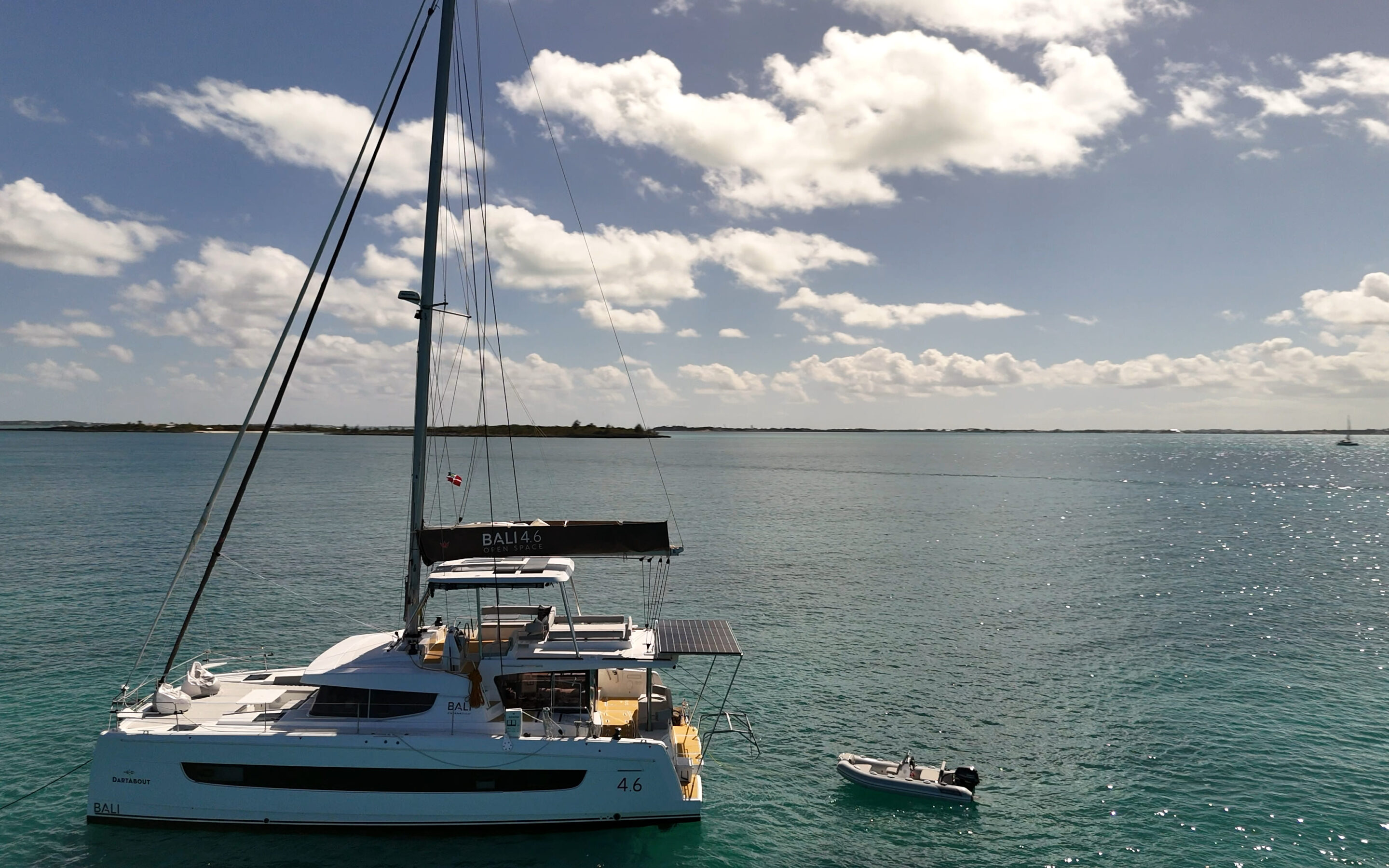 A sleek catamaran gliding across the serene ocean waters under a clear blue sky.