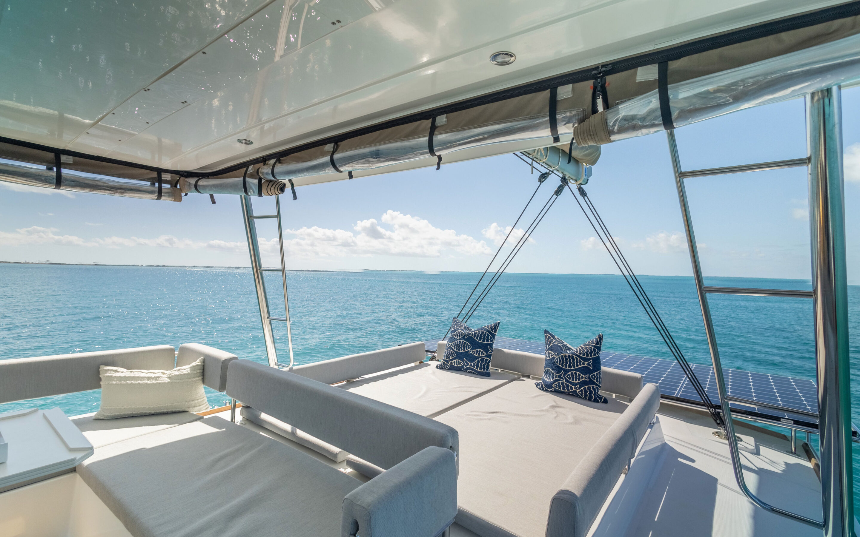 A scenic view from a boat's top, featuring a cozy couch and a table, surrounded by water and open sky.