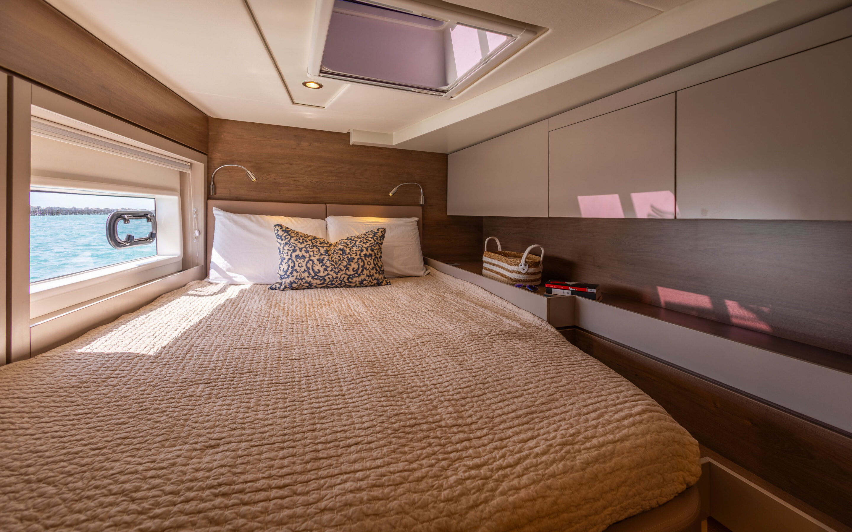 A luxurious master cabin on a catamaran, featuring elegant furnishings and panoramic windows for stunning ocean views.
