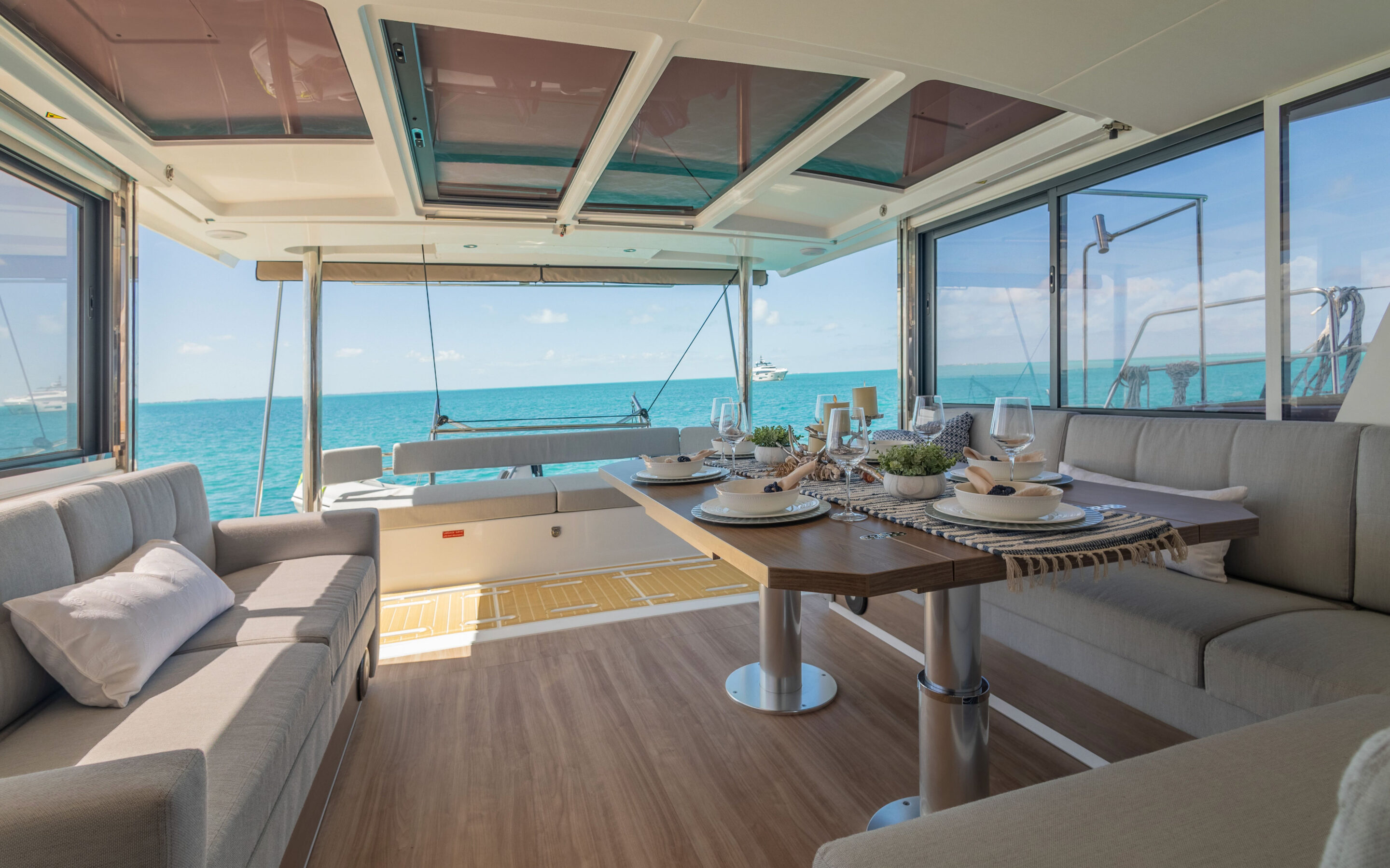 Interior view of a catamaran featuring a dining table surrounded by chairs, showcasing a cozy nautical atmosphere.