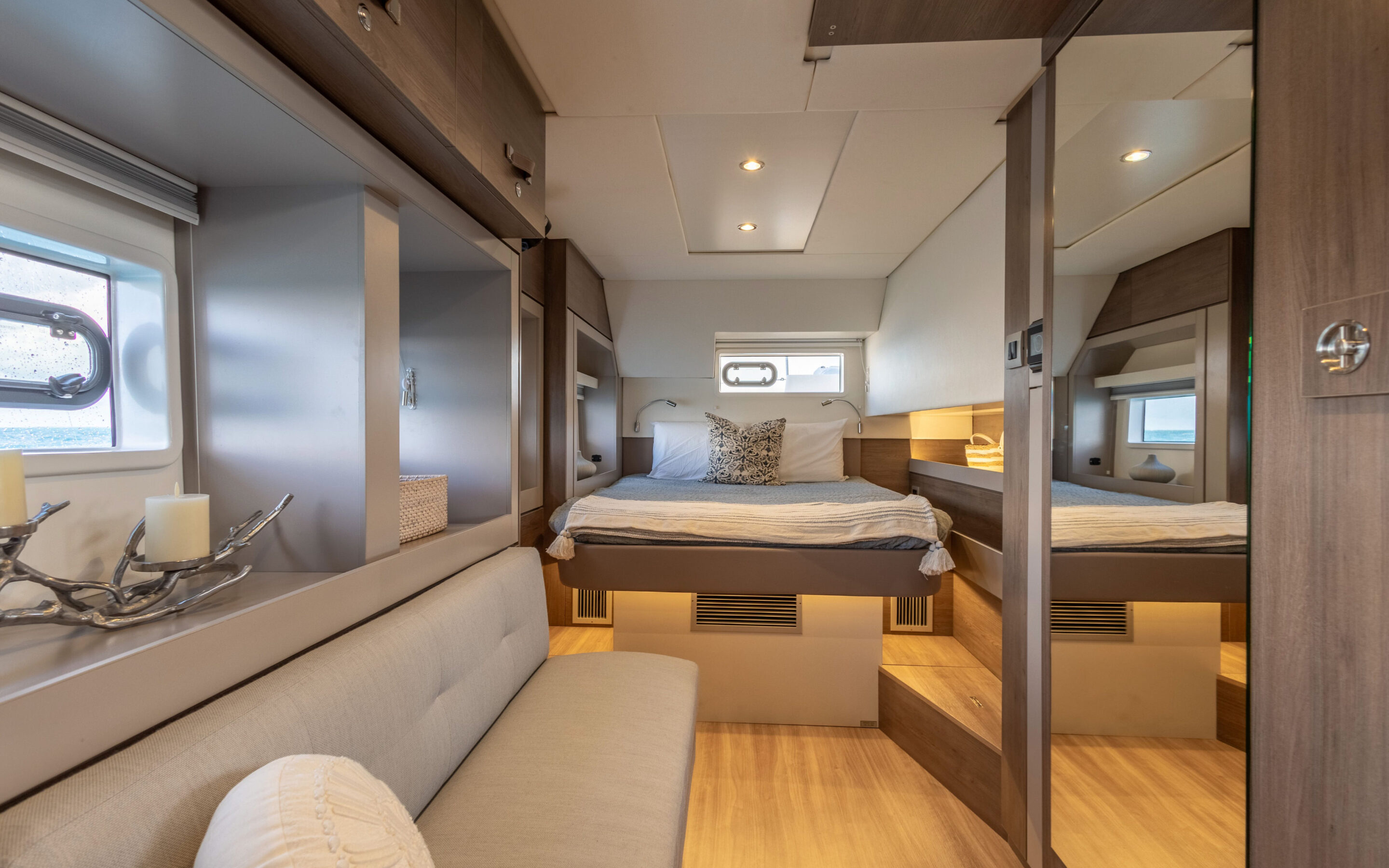 Interior view of a boat featuring a cozy bed and a comfortable couch, showcasing a serene maritime atmosphere.