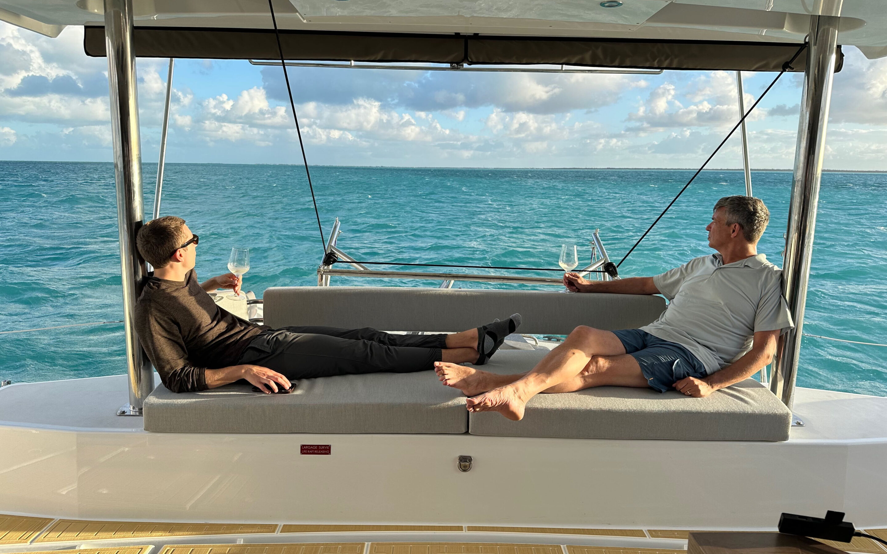 A man and woman enjoy a peaceful moment together on the deck of a boat, surrounded by water and sunshine.