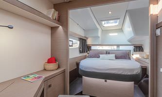 A boat's interior displaying a comfortable bed alongside a practical desk, illustrating efficient use of space.