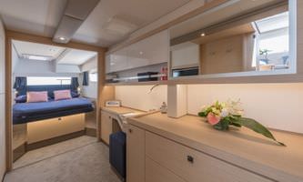 Interior view of a catamaran featuring a cozy bed and a functional desk for work or leisure activities.