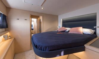 A luxurious yacht bedroom featuring elegant decor, plush bedding, and large windows showcasing a serene ocean view.