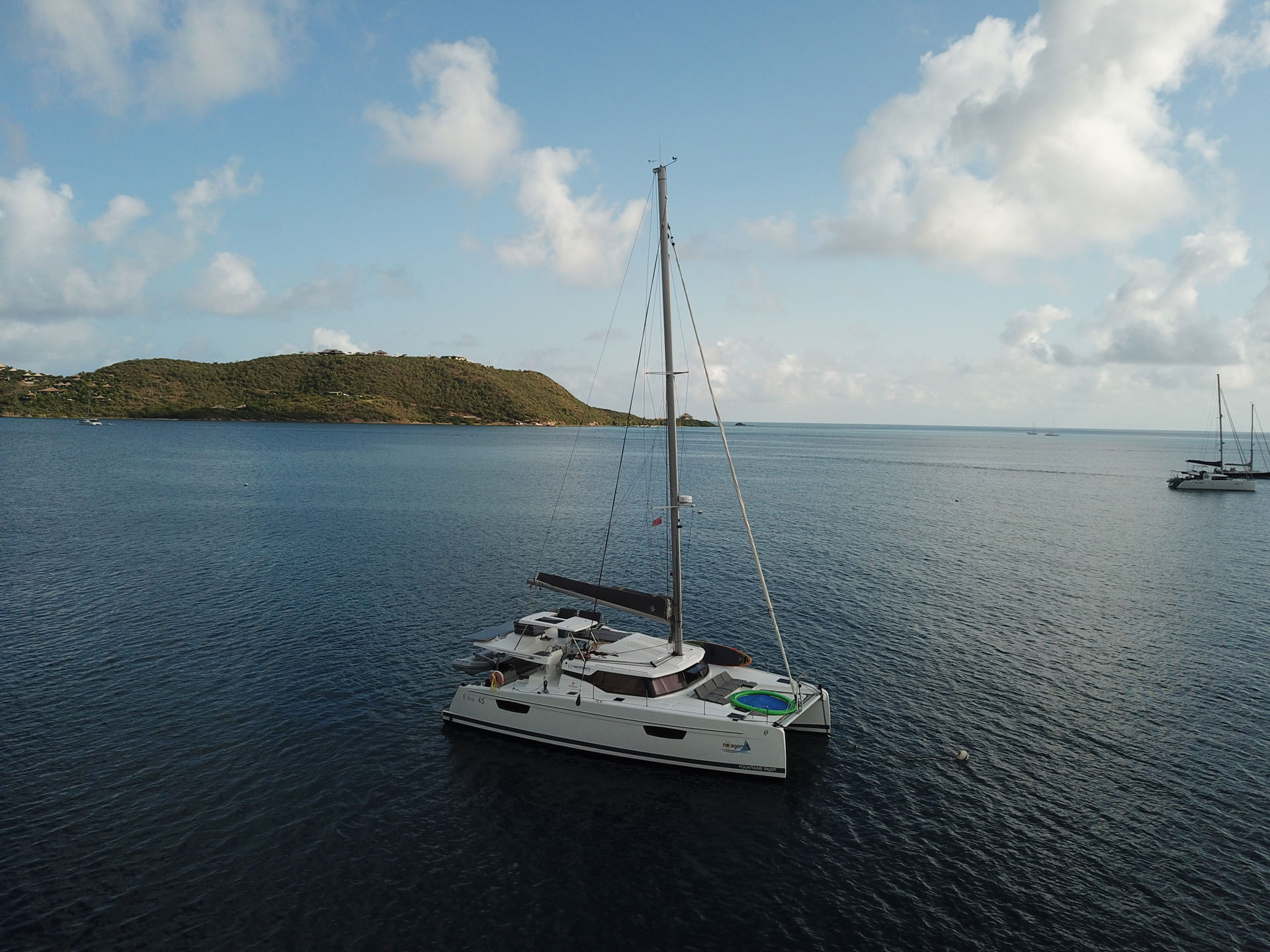 A catamaran anchored peacefully in the open water, surrounded by calm waves and a clear blue sky.