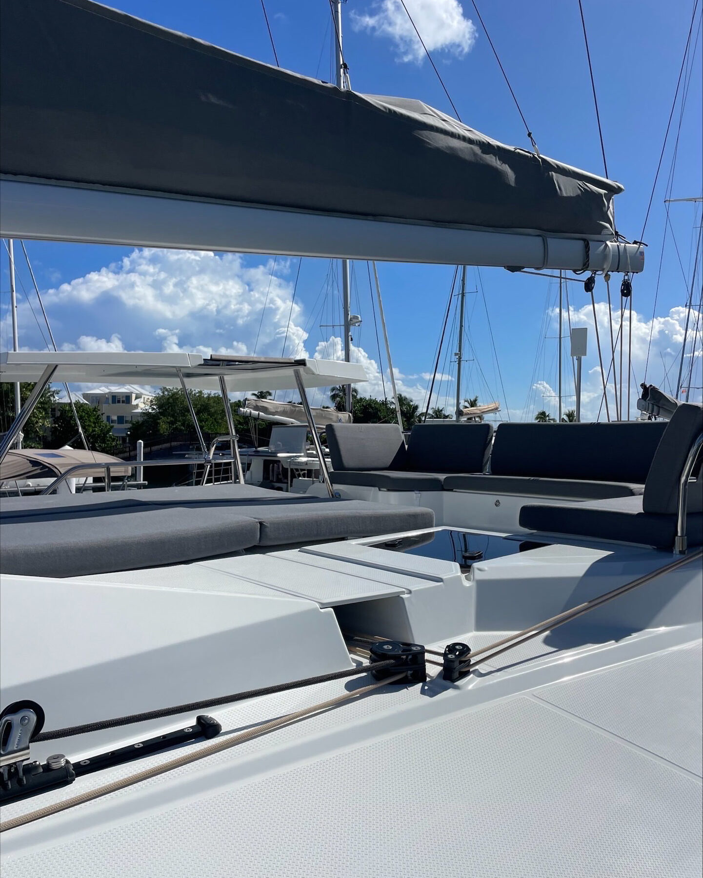 The bow of a sailboat is visible, with sails fully raised, catching the wind against a clear blue sky.