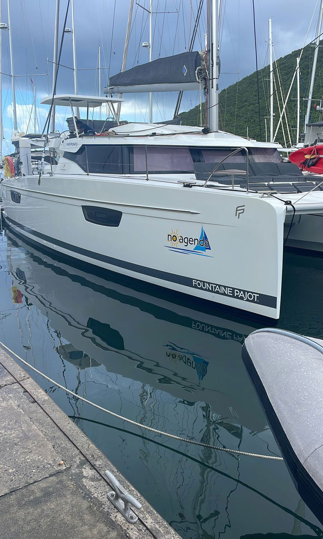 A catamaran is securely docked at a marina, surrounded by calm waters and a clear blue sky.