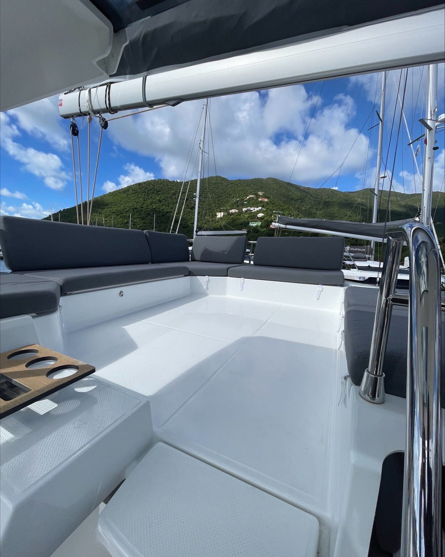 The cockpit of a catamaran boat offers a scenic view of majestic mountains in the background.