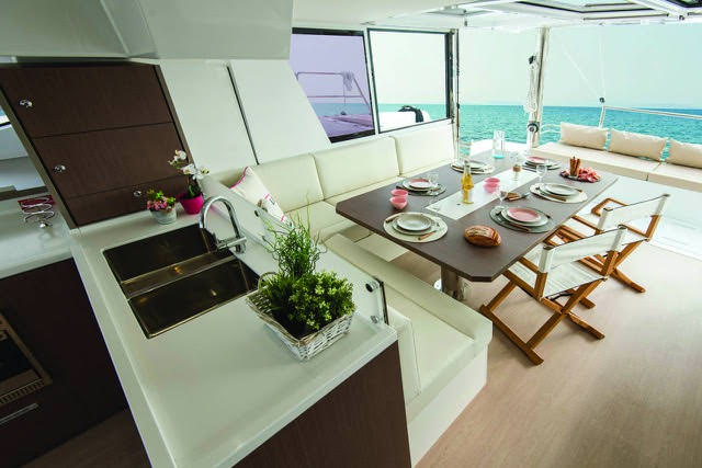 The interior of a boat featuring a dining table surrounded by chairs, showcasing a cozy and inviting atmosphere.