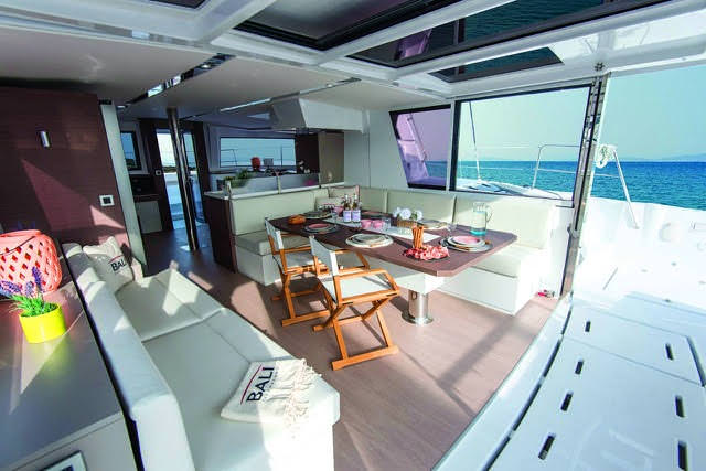 Interior view of a boat featuring a dining table surrounded by chairs, showcasing a cozy and inviting atmosphere.