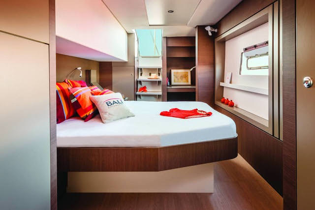 A cozy boat interior featuring a comfortable bed and a functional desk, showcasing a serene maritime atmosphere.
