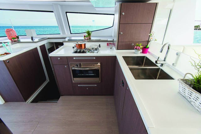 A cozy kitchen and dining area on a boat, featuring a compact layout with nautical decor and a view of the water.