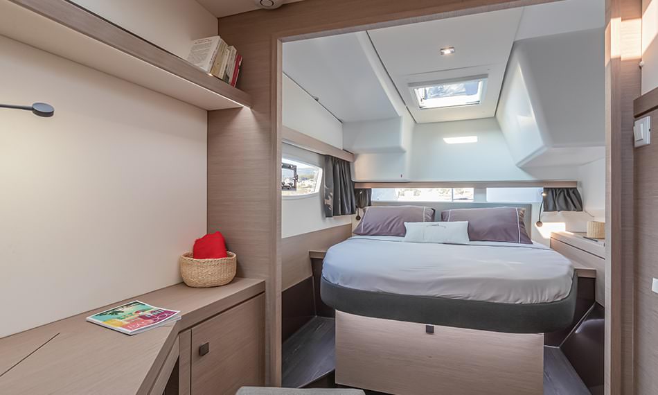 Inside a small boat, a bed and desk are arranged to create a functional and inviting living area.