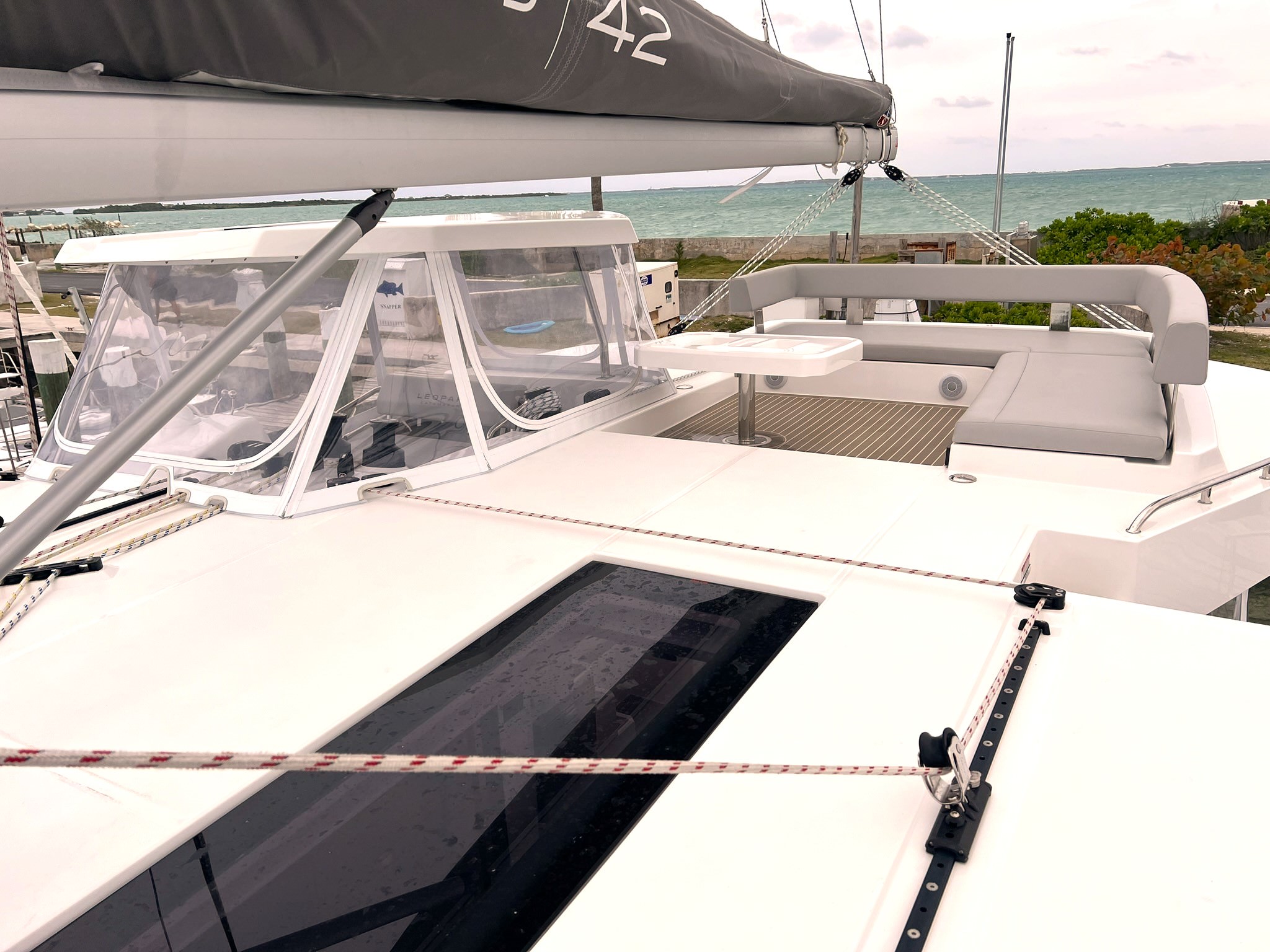 Serenity – Exterior 03 A sleek catamaran featuring a dark gray sail, navigating through serene waters on a sunny day.