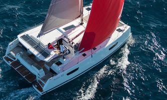 A sleek catamaran sailing on the open ocean, surrounded by sparkling water and a bright, sunny atmosphere.