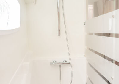 A modern bathroom displaying a shower with a white curtain, highlighting simplicity and elegance in design.