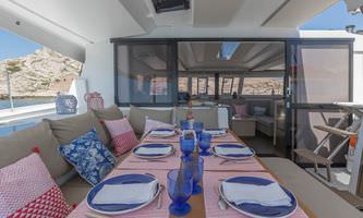 A dining table set on the deck of a catamaran, surrounded by ocean views and a serene atmosphere.