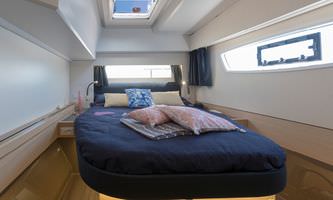Interior of a boat featuring a cozy bed beside a window, showcasing a serene and inviting atmosphere.