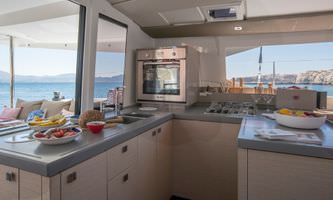 A cozy kitchen and dining area on a boat, featuring compact appliances and a table with seating for a nautical dining experience.