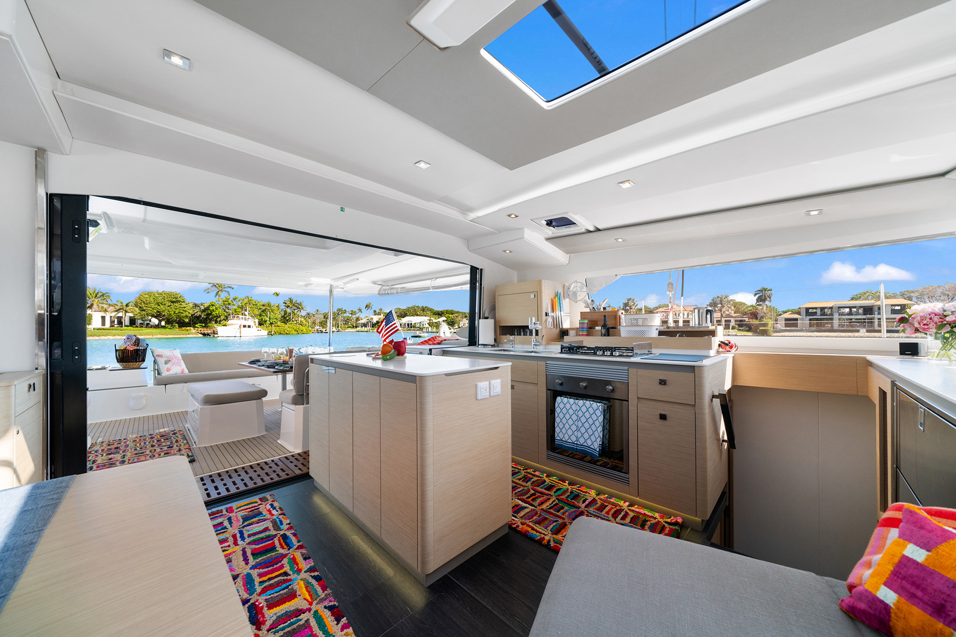 Interior view of a boat featuring a cozy kitchen and living room area, showcasing nautical decor and comfortable furnishings.