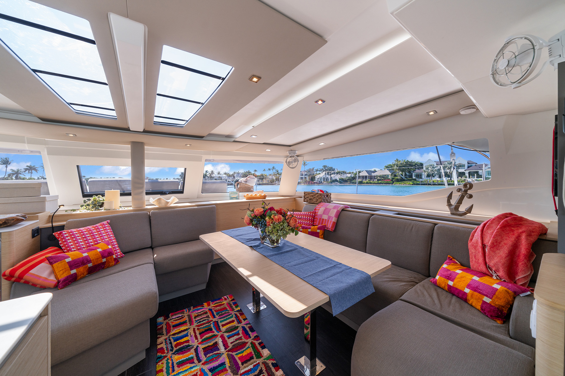 Inside a boat, a generous table and a soft couch provide a welcoming space for leisure and conversation.