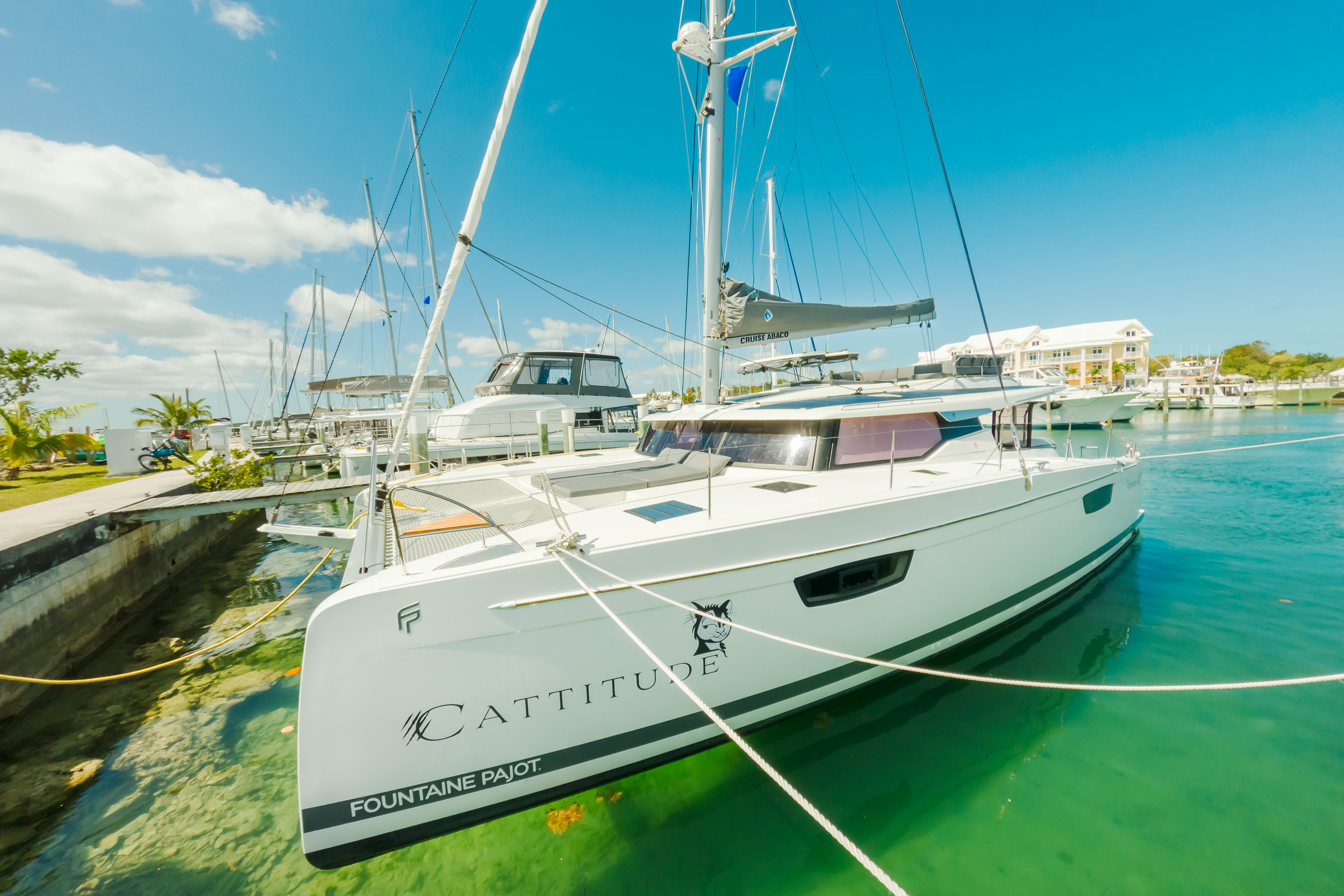 A sailboat is docked at a marina, surrounded by calm water and other boats in the background.