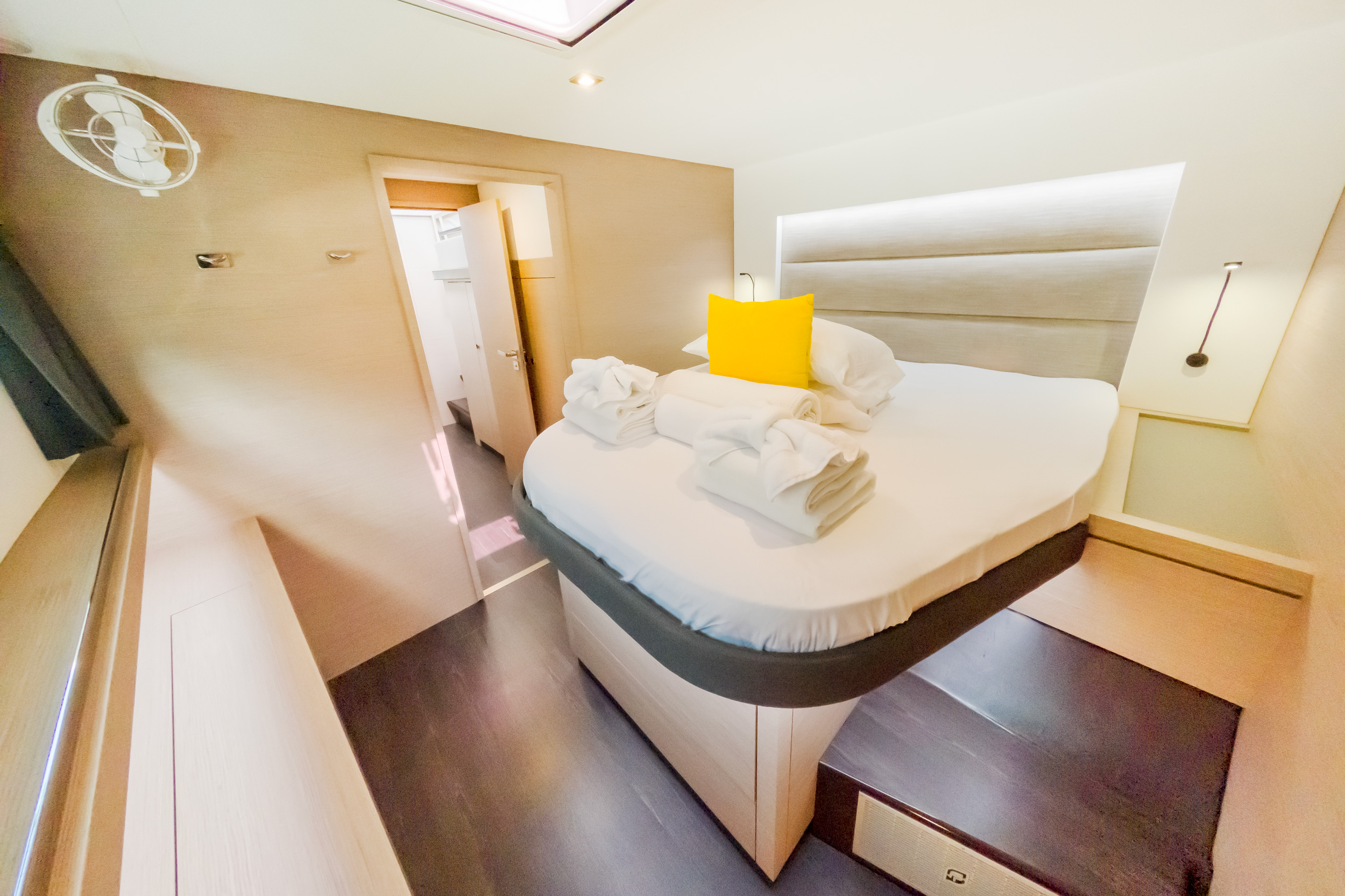 A neatly made bed featuring a yellow pillow and a folded white towel on top.