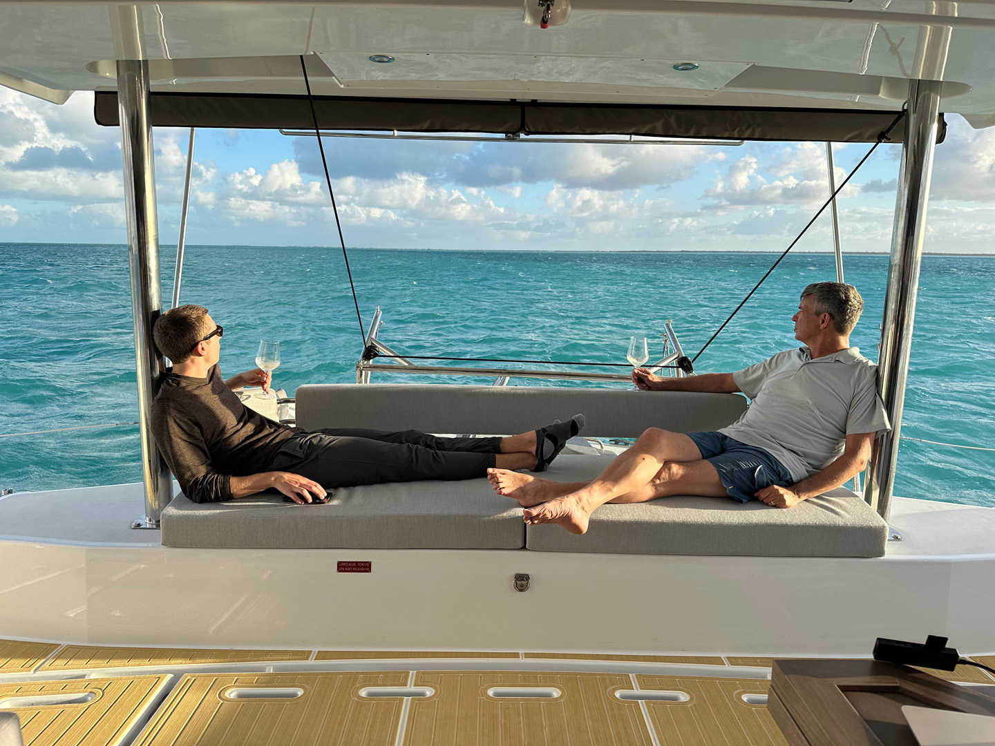 Two people relaxing together on the deck of a boat, enjoying the serene water view and sunny weather.