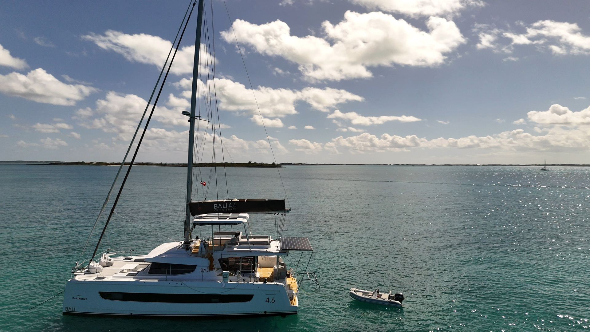 A catamaran sailing smoothly across the blue ocean under a clear sky.