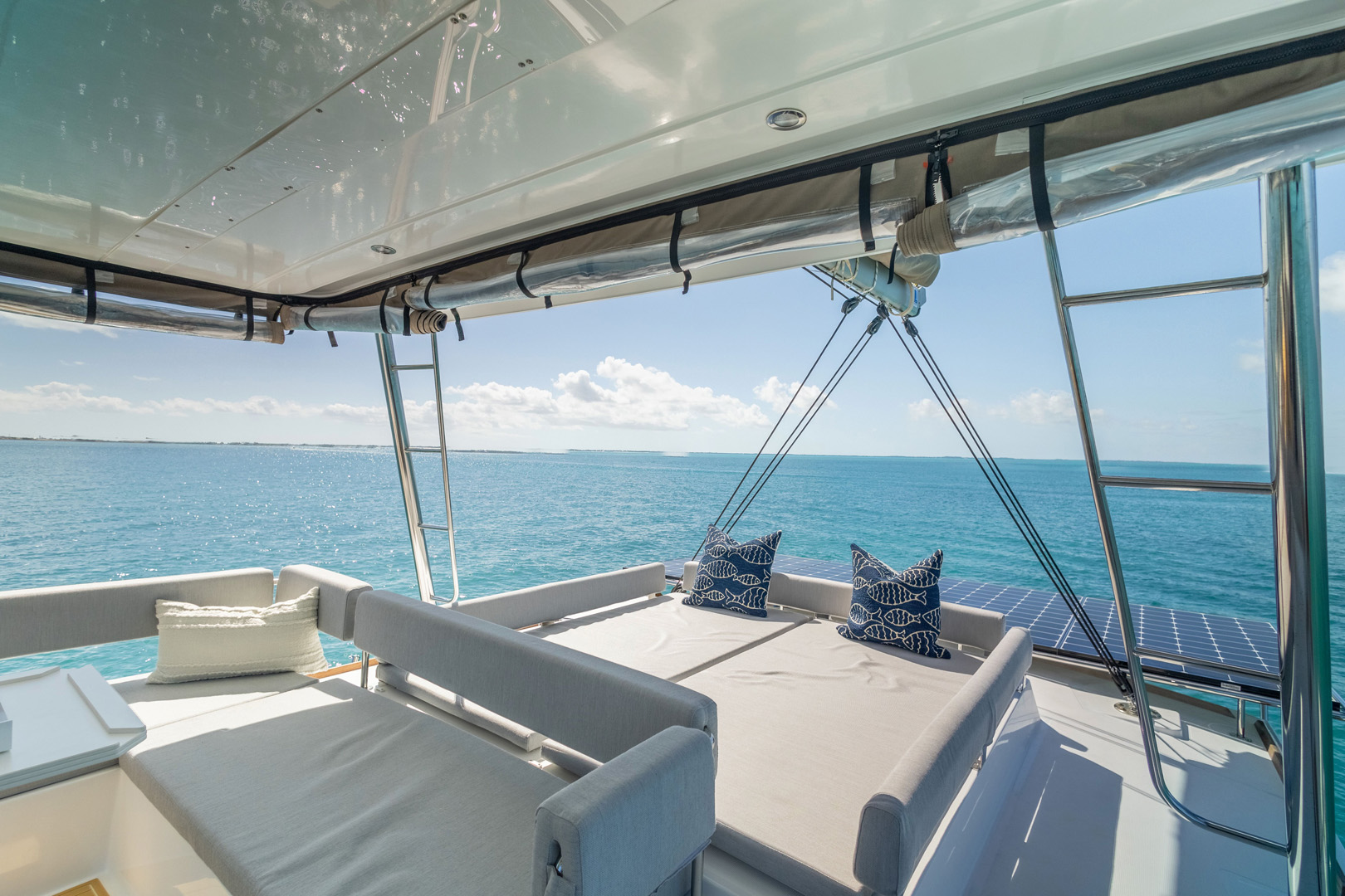 View from a boat's top deck featuring a couch and table, surrounded by water and a clear sky.