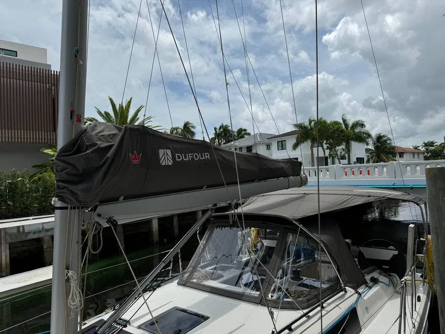 A sailboat with a protective cover is moored at the dock, ready for use.