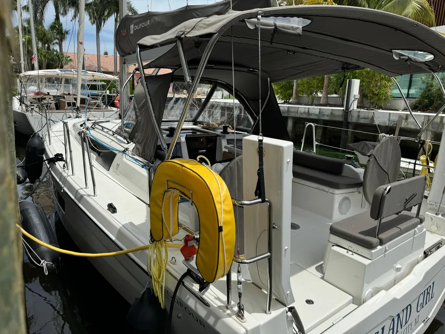 A sailboat rests at the dock, tied with a yellow rope for stability.