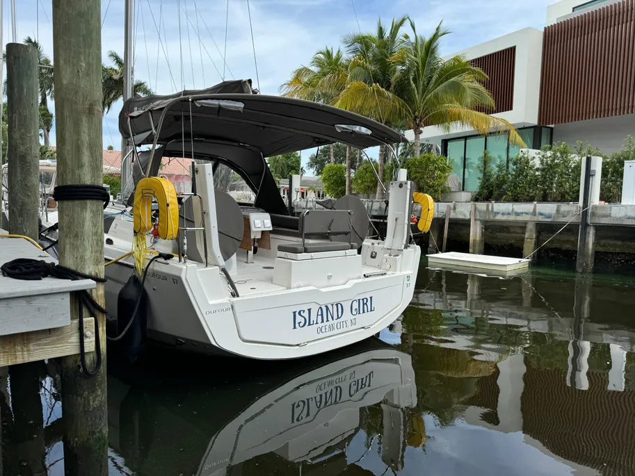 A boat is docked at a pier surrounded by palm trees, with a clear blue sky in the background.