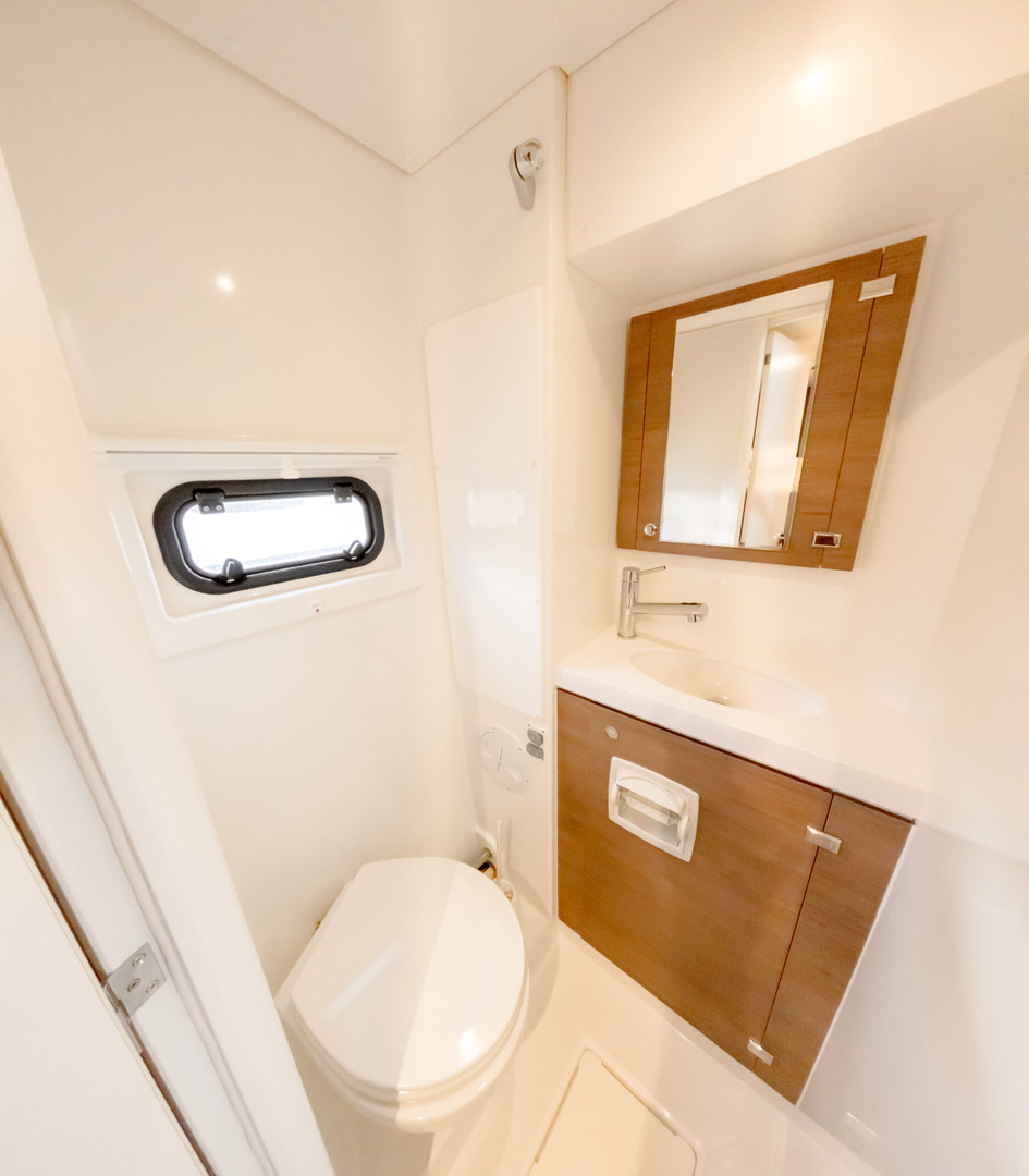 A yacht bathroom featuring a toilet, sink, and mirror, designed for compact luxury and functionality.